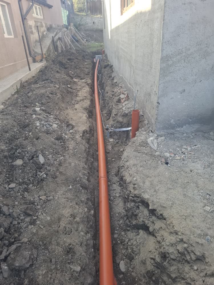 Canalizare pe lângă fundația casei, în șanț îngust săpat între două clădiri.