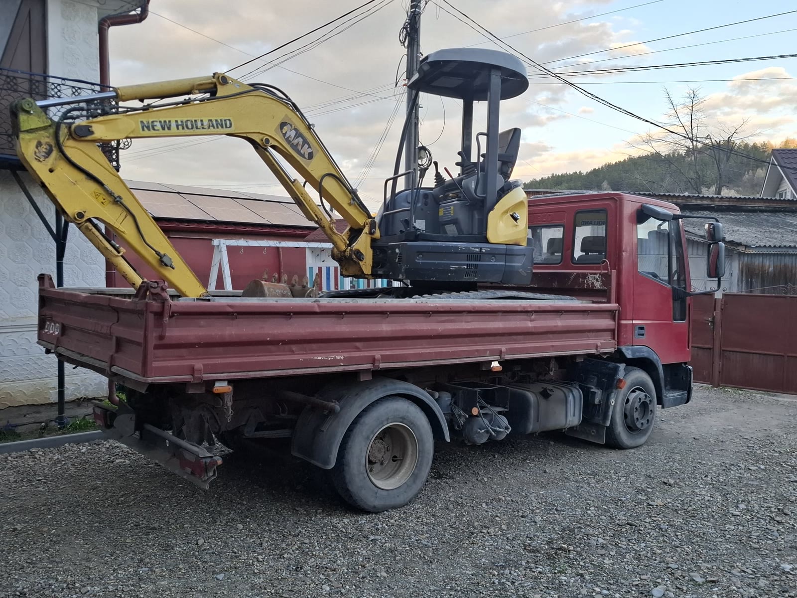 Miniexcavatorul New Holland pe șenile, încărcat în bena camionului IVECO basculabil